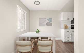 a dining area with a white table and four chairs and a kitchen in the background
