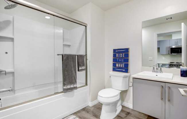 Bathroom of a studio apartment with hot tub and shower combo, single vanity, wood style flooring