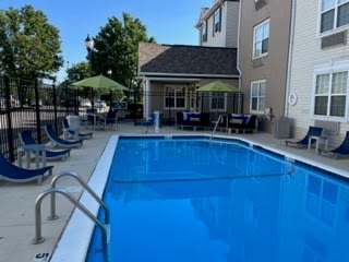 a swimming pool with chairs and umbrellas in front of a building