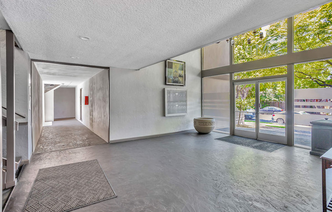 A hallway with a rug on the floor and a wall with a mirror on the side.