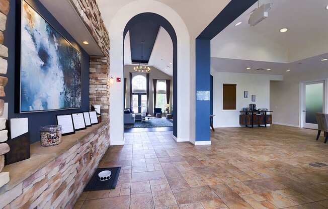 A hallway with a stone wall and a large painting on the wall.