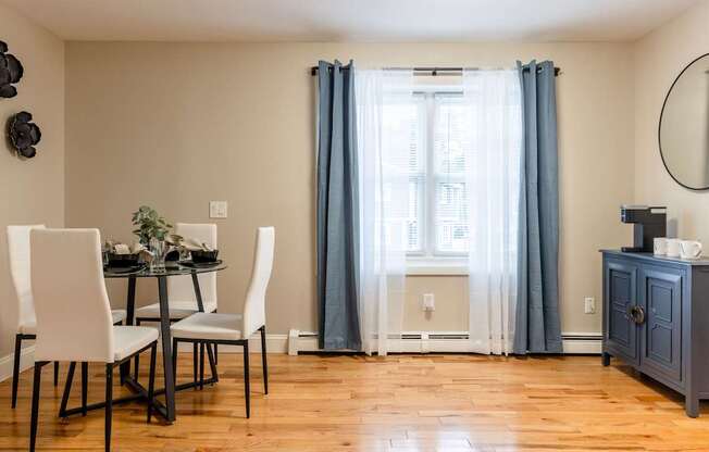 A dining room with a table set for two and a window with curtains.