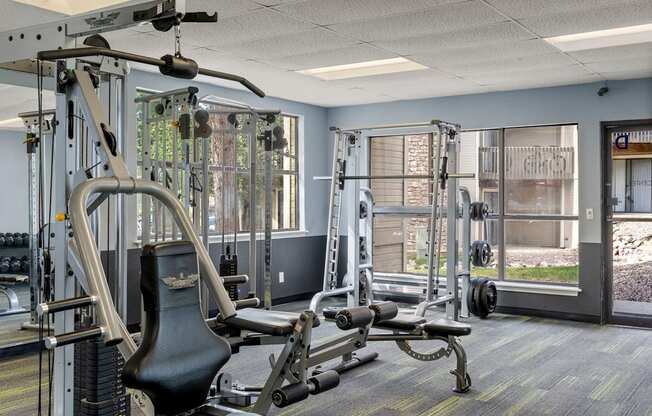 A gym with a variety of equipment including a weight bench, a cable machine, and a squat rack.