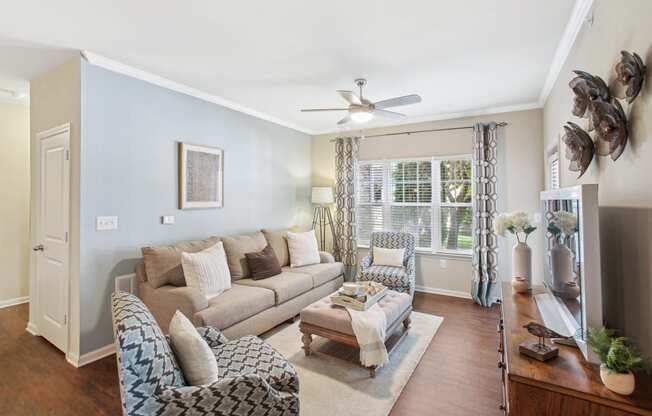 a living room with a couch and chairs and a ceiling fan