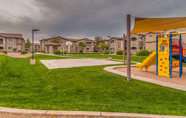Desert Sands playground and basketball court surrounded by green grass.