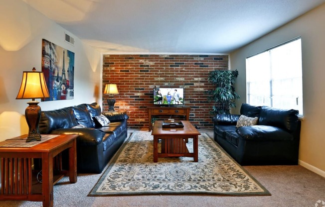 a living room with leather furniture and a brick wall