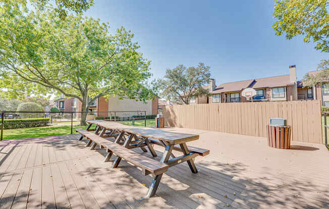 A wooden picnic table is in the middle of a paved area.