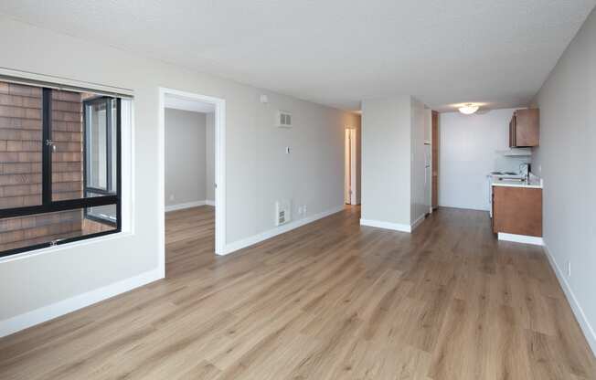 a living room with hardwood floors and a kitchen in the background