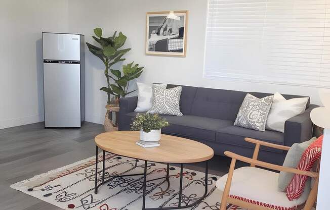 A living room with a grey couch, a wooden coffee table, and a ceiling fan.