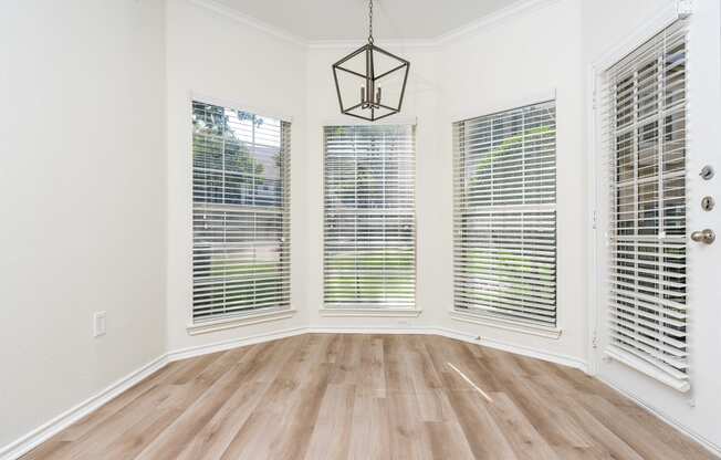 an empty dining room with four windows and a chandelier