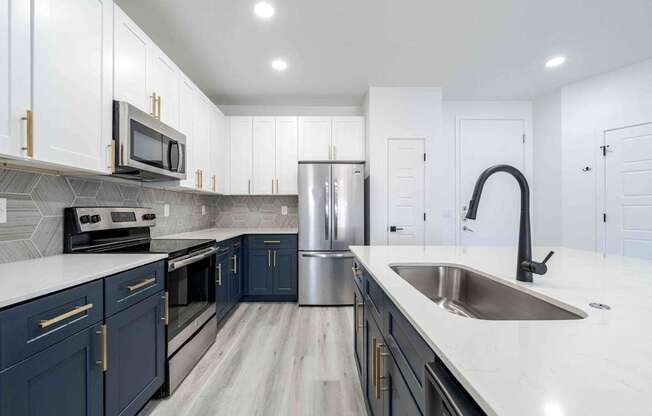 a kitchen with blue and white cabinets and stainless steel appliances