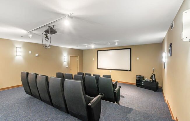 a theater room with a projector screen and chairs