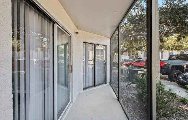 A balcony with glass doors and a view of a parking lot.