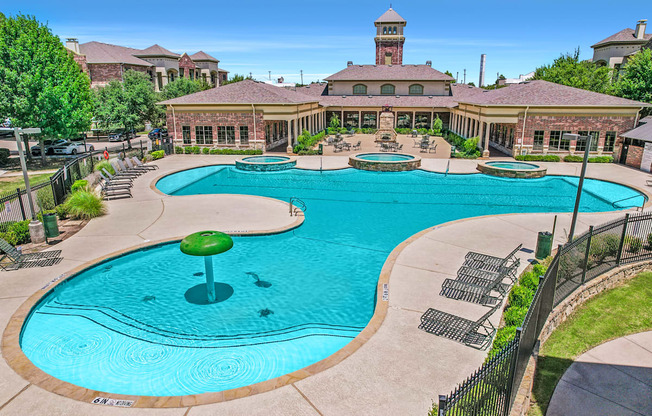 A large swimming pool with a water slide and a building in the background.