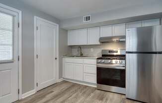 A modern kitchen with a stainless steel refrigerator, oven, and cabinets.