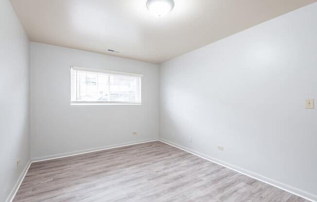 A room with a window and wooden flooring.