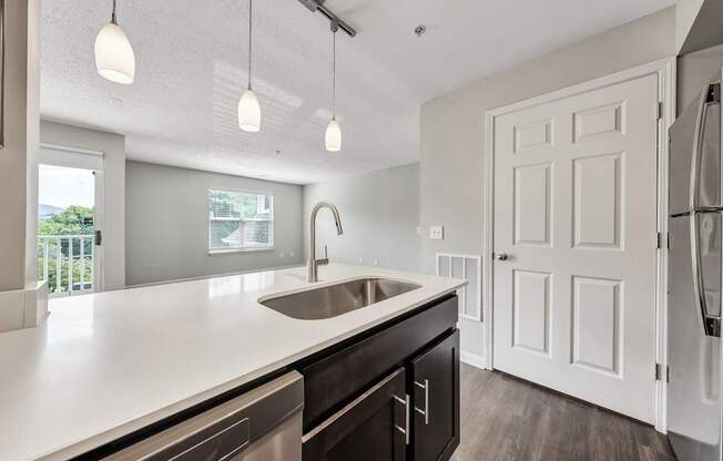 A modern kitchen with a white countertop and a stainless steel sink.