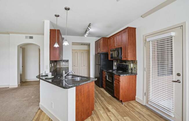 A kitchen with wooden cabinets and a black countertop.