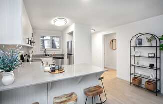 an open kitchen with a white counter top and a large island with two stools at Brix, Washington, 99362