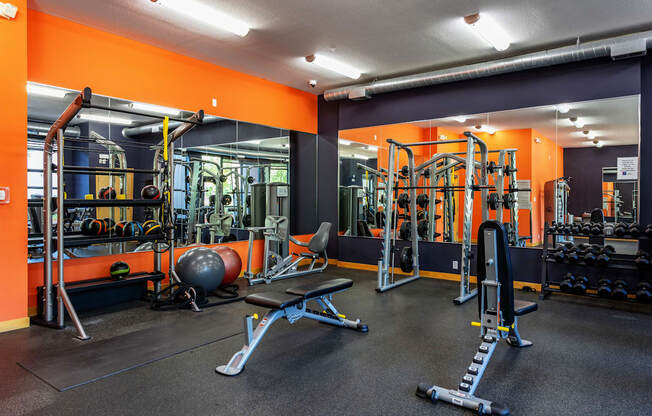 A gym with orange walls and a variety of equipment.