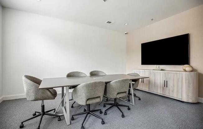 A conference room with a table, chairs, and a television.