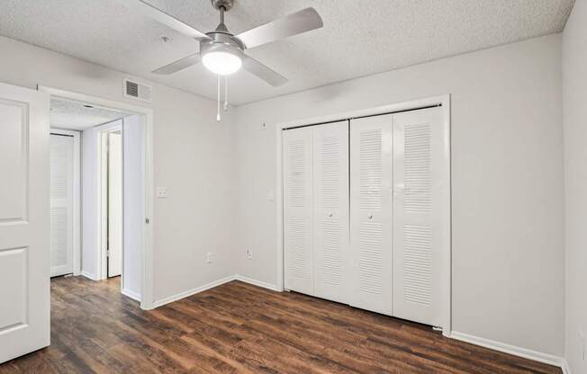 A room with a ceiling fan and wooden floors.