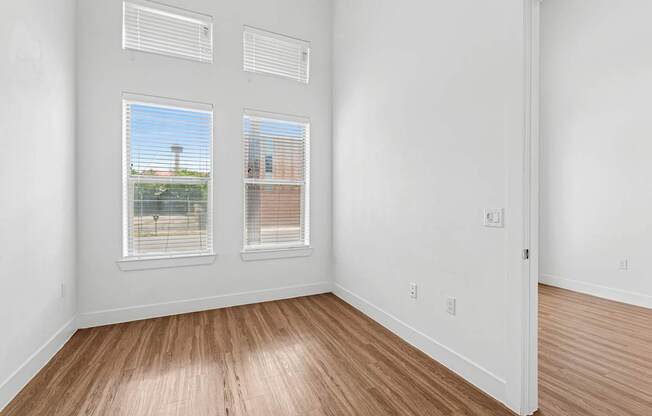 A room with two windows and wooden floors.
