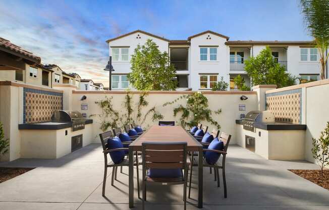Riverside, CA Apartments for Rent - Lincoln Village - Gated BBQ Grilling Area With 10 Person Table, 2 Grills, Green Plants, And Stylish Decor