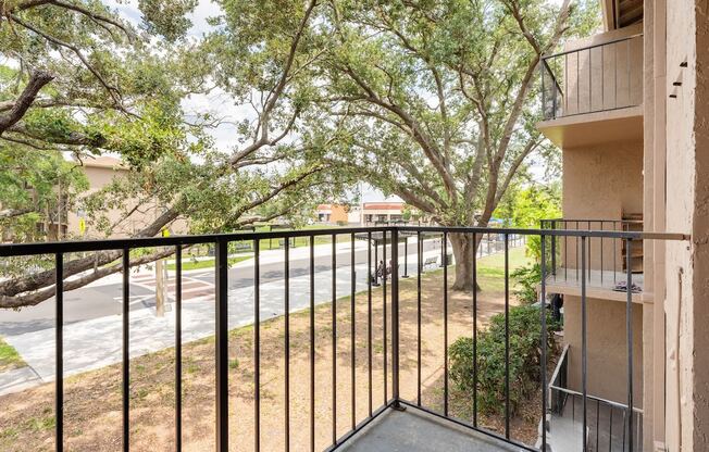 the view from the balcony of an apartment building with a yard and trees