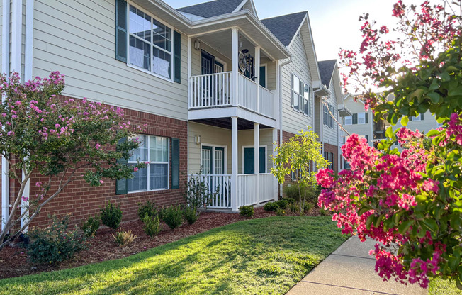 an exterior view of an apartment building with a lawn and flowers