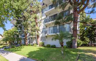 an apartment building with a lawn and trees in front of it