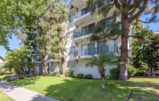 an apartment building with a lawn and trees in front of it