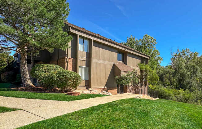 A house with a brown siding and a large tree in front.