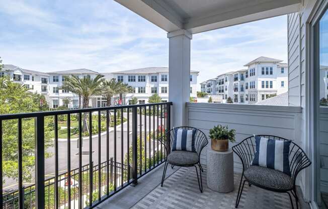 a balcony with two chairs and a view of a building and a beach at Altis Grand Lake Willis, Orlando, 32821