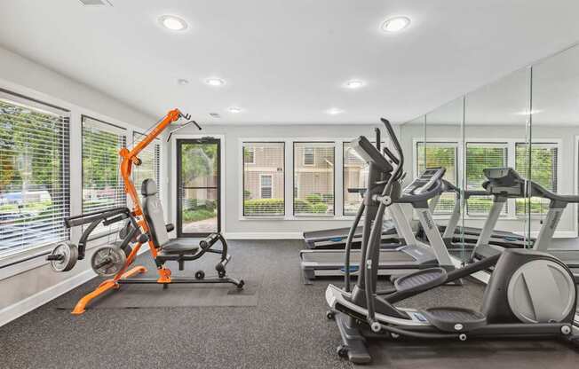 A gym with a row of treadmills and a row of stationary bikes.