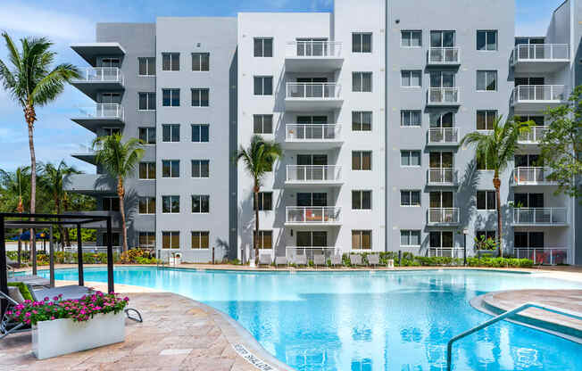 A large white apartment building with a pool in front.