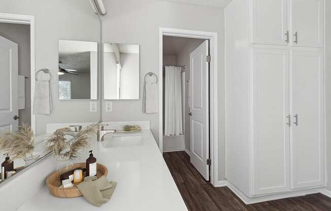 Model Bathroom with White Cabinets and Wood-Style Flooring at Colonnade at Fletcher Hills Apartments in El Cajon, CA.
