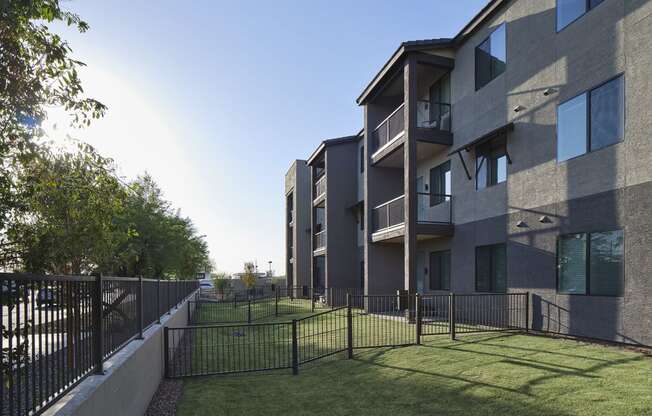 an apartment building with a yard and a fence