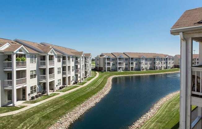 A row of white apartment buildings with a river running through the front.