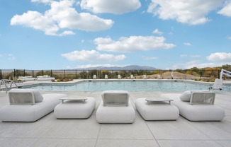 a group of white couches next to a swimming pool