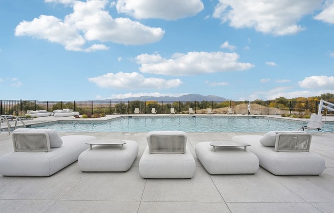 a group of white couches next to a swimming pool