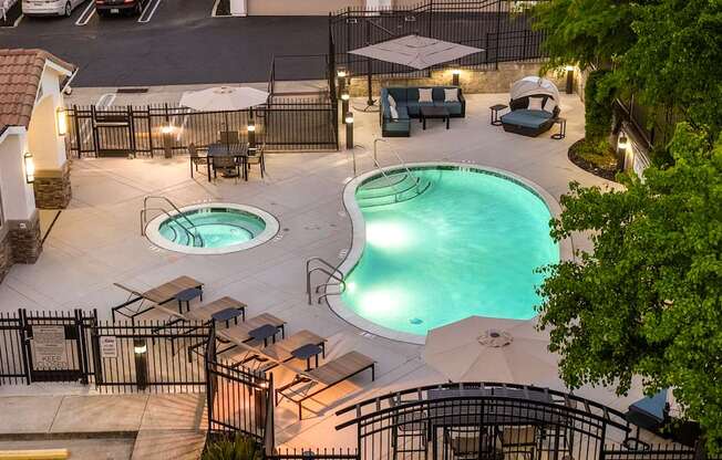 A pool area with two pools and a hot tub surrounded by a fence.