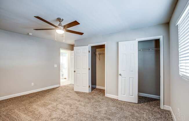 a bedroom with a ceiling fan and two closets