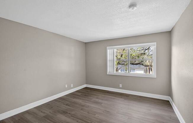 A room with a window and wooden flooring.