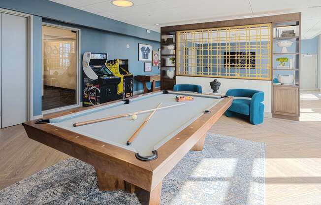 a games room with a pool table and a arcade game