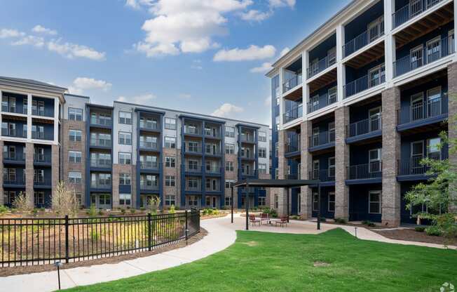 an exterior view of an apartment building with green grass and a walkway at Preston Ridge Cary, NC