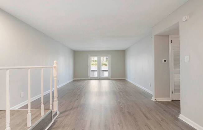 A spacious room with light wood flooring and white walls.