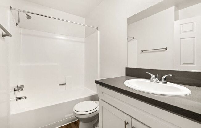 A white bathroom with a toilet, sink, and shower.
