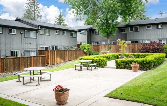 an outdoor patio with picnic tables in front of an apartment building