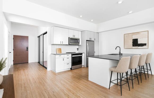 Kitchen with quartz countertops, bar seating, and streamlined cabinetry opening to a bright living area with natural light and clean finishes.